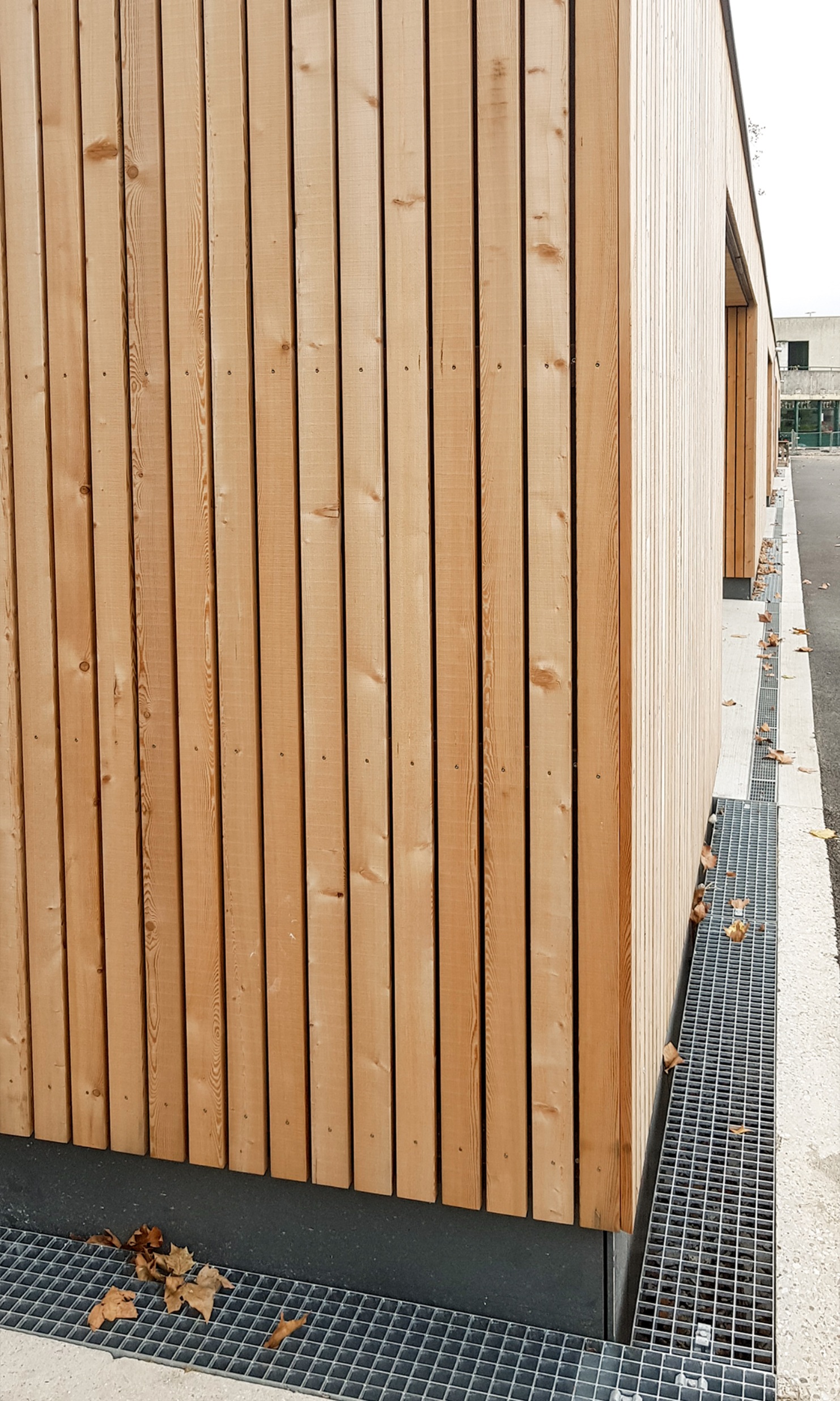 Ecke mit Holzfassade des eingeschossigen Erweiterungsbaus mit Umkleideräumen