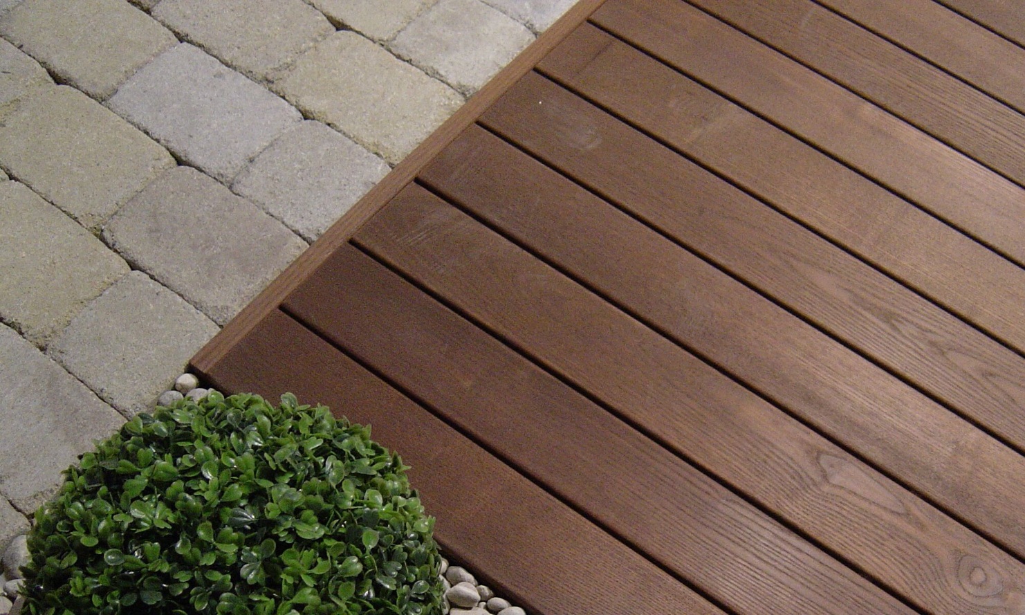 Vue détaillée d’une terrasse en bois dur à côté d’une plante verte avec jardin de rocaille