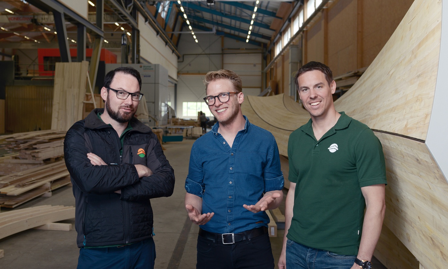 Groupe de personnes en reconversion dans la halle de production avec un objet en bois en arrière-plan