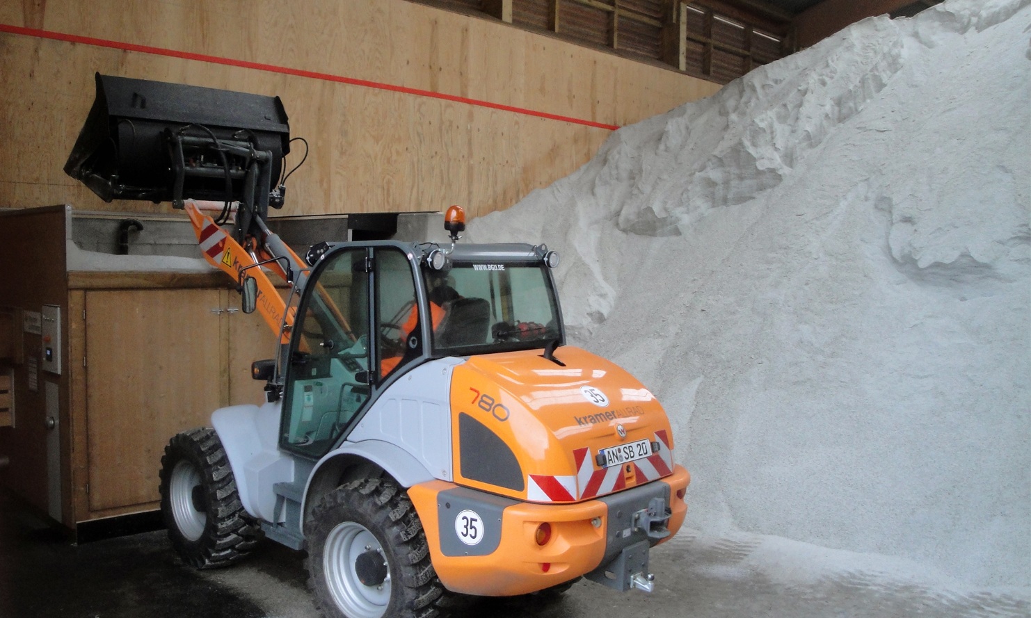 A front loader feeds a module conveyor system with salt