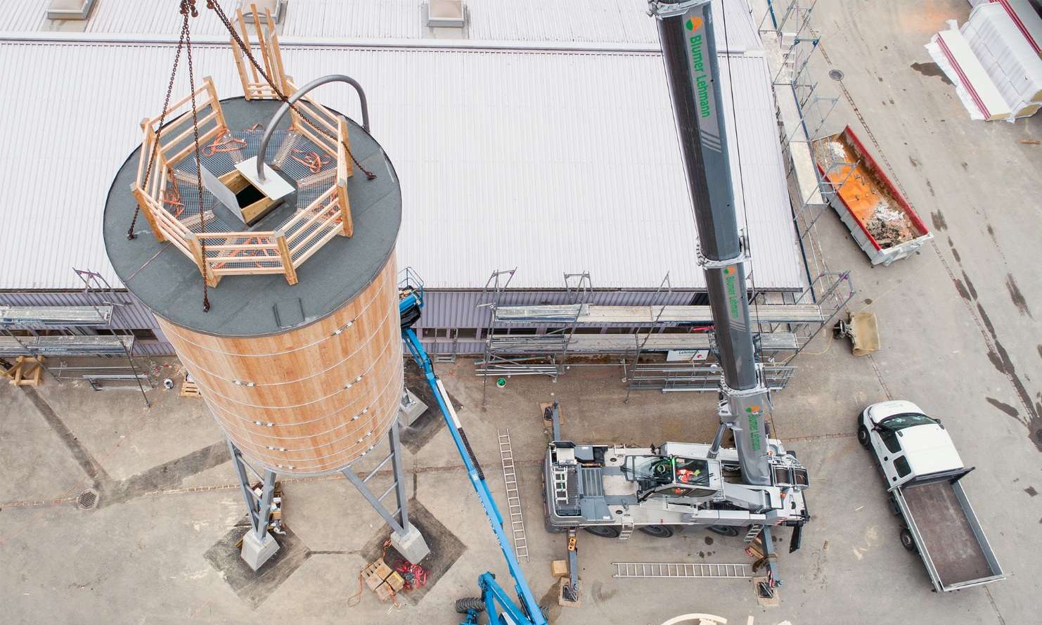 Round timber silo suspended from a crane, seen from above