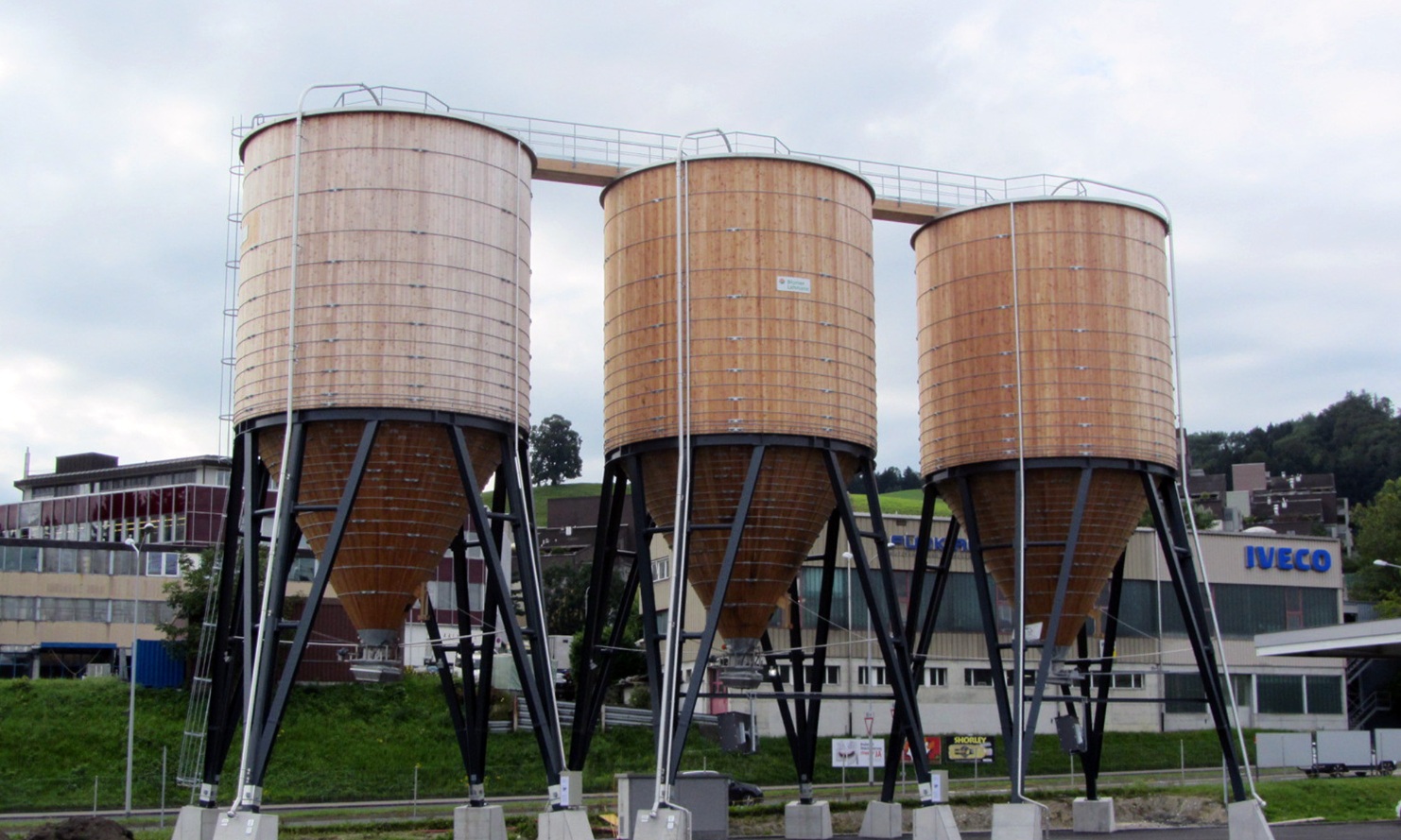 Drei runde Silos aus Holz nebeneinander platziert und mit Dachübergang miteinander verbunden, St.Gallen Neudorf