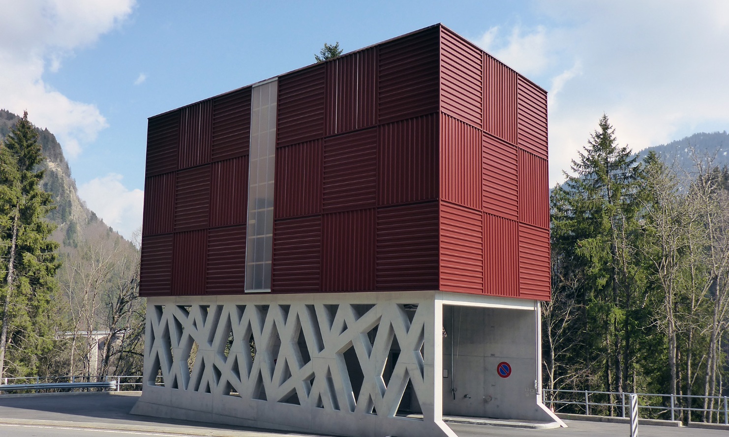 Roter architektonischer Modulsilo mit filigranem Betonunterbau, wodurch eine Strasse führt