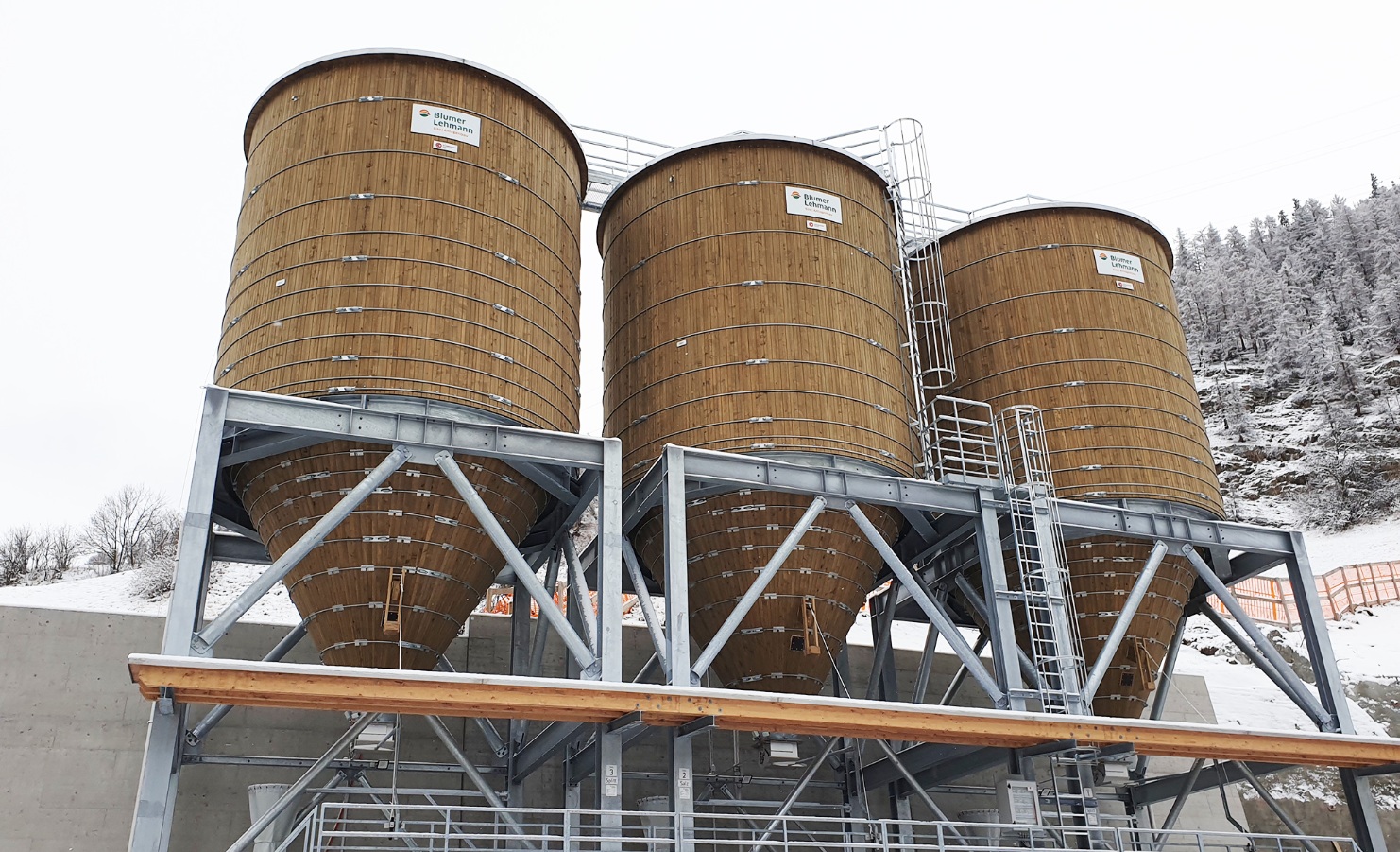 Drei runde Streugutsilos aus Holz für die Lagerung von Salz und Splitt in Zernez