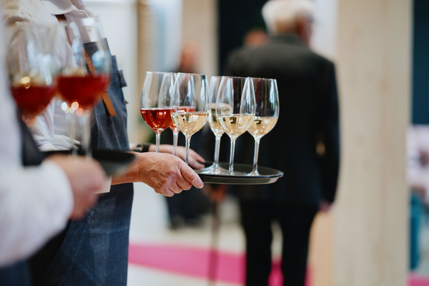 Servicepersonal mit Tabletts voller Weiss- und Rosewein-Glaeser beim Apero zum 150-jaehrigen Jubilaeum von Blumer Lehmann.