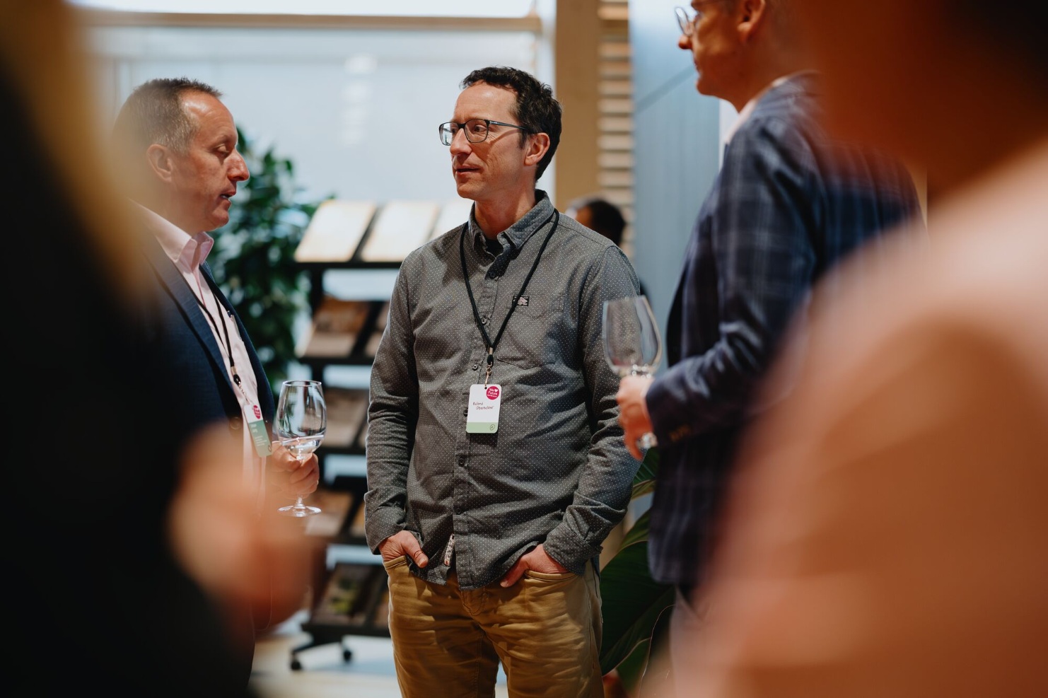 Gaeste im Gespraech mit Weinglaesern beim 150-jaehrigen Jubilaeum von Blumer Lehmann – lockere Networking-Atmosphaere.