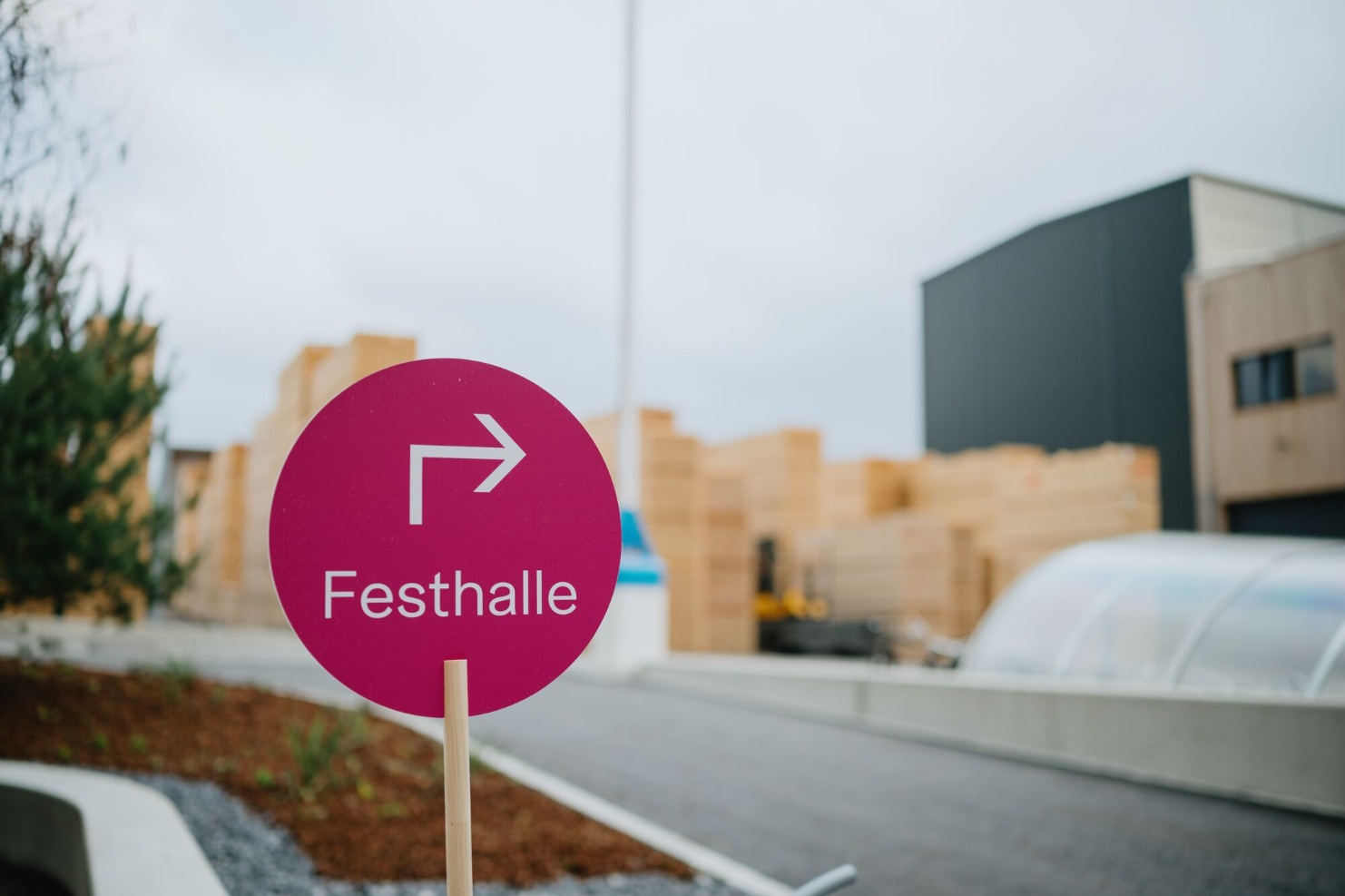 Pinkes Wegweiser-Schild mit Pfeil und der Aufschrift „Festhalle“ auf dem Firmengelaende von Blumer Lehmann beim 150-jaehrigen Jubilaeum.