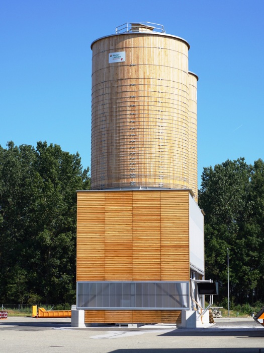 Silos en bois ronds pour le service hivernal à Domdidier avec une façade en bardage à clin en mélèze et des panneaux translucides en polycarbonate