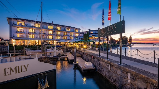 Hotel Bad Horn mit hell erleuchteten Fenstern und mit Schiffsteg sowie Booten davor