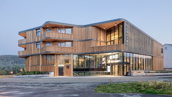 Dreistöckiges Bibliotheksgebäude Samling mit geschwungener Form in Holzbauweise bei Abendstimmung 