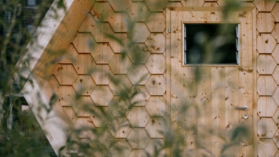Detailansicht der Holzeingangstüre und Fassade mit wabenförmigen Holzschindeln