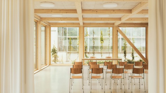 Blick in den hellen Vortragsraum mit Holzstühlen 