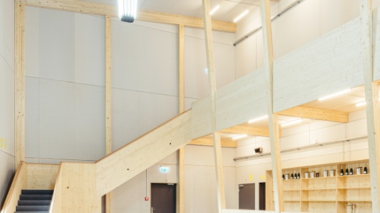 Heller Eingangsbereich mit viel sichtbarem Holz im Theaterprovisorium St. Gallen, mit Foyer, Treppe und Bar. 