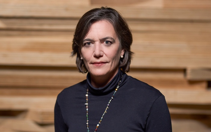 Portrait photo of Katharina Lehmann in front of a stack of wooden slats