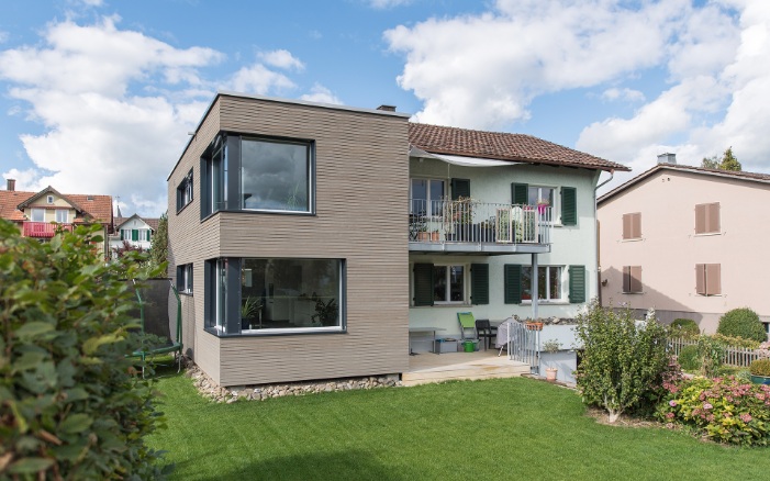 Gesamtansicht des Einfamilienhauses mit modernem Anbau und Garten im Wohnquartier.