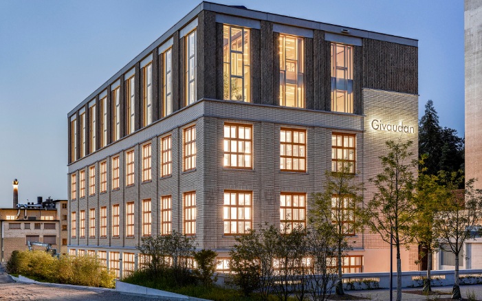 Vue extérieure de l’immeuble de bureaux de Givaudan, récemment transformé, avec des fenêtres très éclairées.