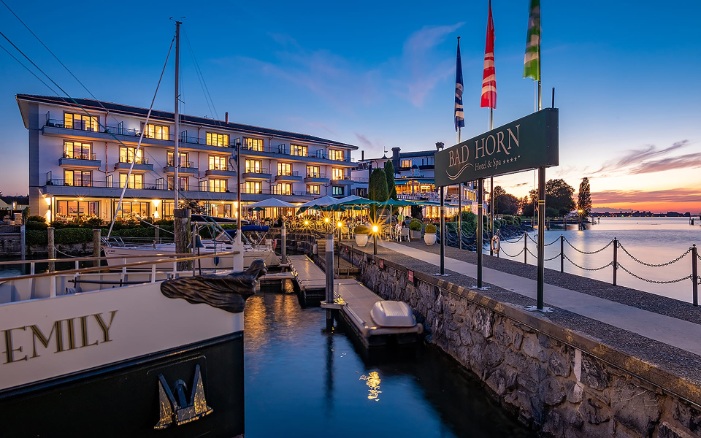 Hotel Bad Horn with brightly lit windows and a jetty and boats in front of it