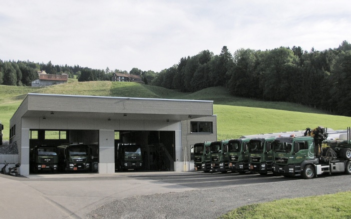 Vue générale du garage de camions avec la flotte de camions stationnés devant.