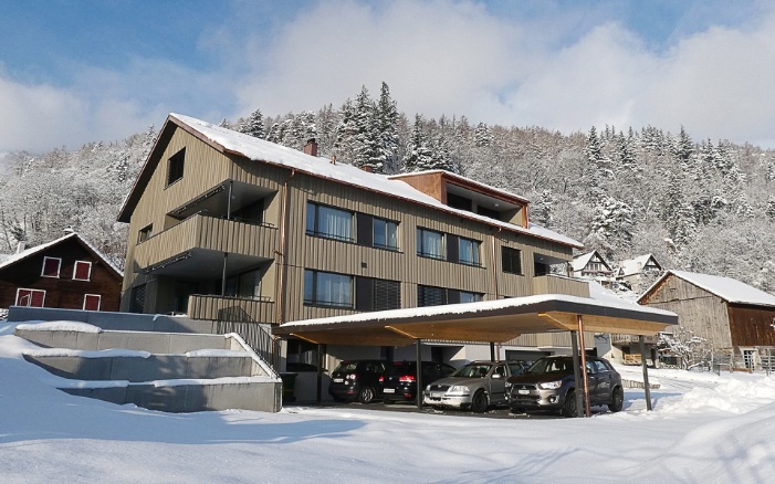 Vue d’ensemble de l’immeuble collectif à Azmoos avec abri pour 4 voitures; en hiver