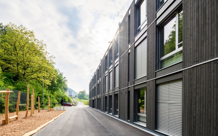 Aussenansicht der Längsfassade des Schulhauses Grenzhof Luzern mit Spielplatz auf der linken Seite