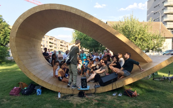 Many people sit or stand together in the sound pavilion, which is in the shape of a loop.