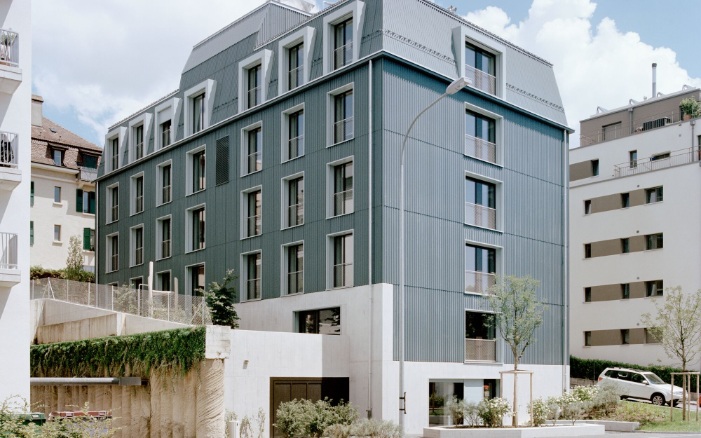 Das Asylzentrum mit Holzfassade und Mansardendach, die typisch sind für den lokalen Baustil. 