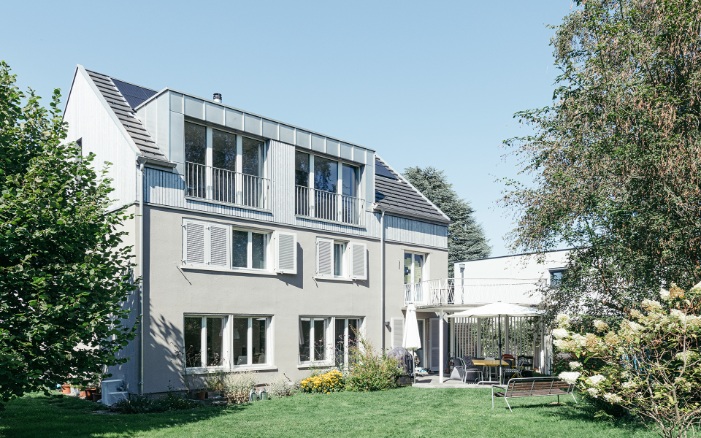 Overall view of the extended detached house with a garden