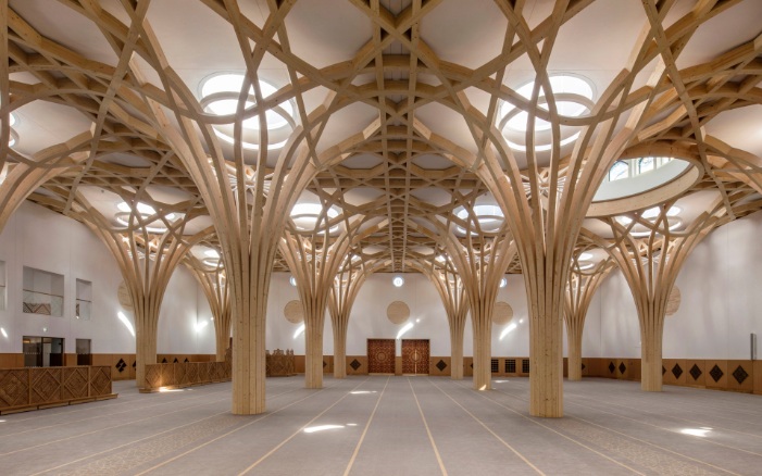 Baumartige Tragstruktur aus Holz und orientalische Holzelemente an Wänden und Türen im Innenbereich der Cambridge Mosque.