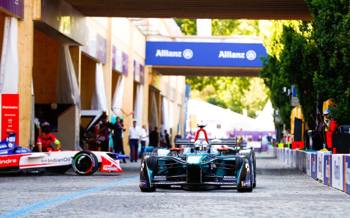 Formula E car in the pit lane. In the background is a blue billboard.