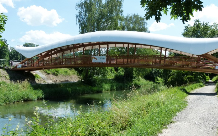 Gesamtansicht der Holzkunstbrücke Aubrugg mit einer weiss-geschwungener Überdachung bei schönem Wetter