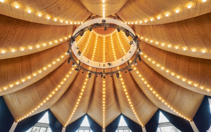 Dessous du toit incurvé en bois à formes libres, avec une guirlande lumineuse à l’intérieur du chapeau de magicien