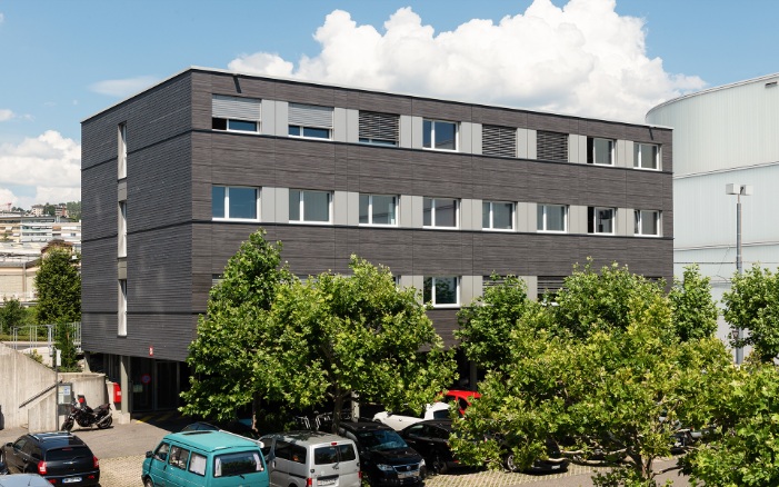 Dreistöckiger Modulbau mit dunkler Holzfassade als Bürogebäude von Lausanne Transport<br/><br/>