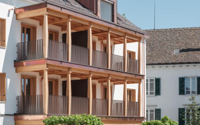 Façade de l’immeuble avec ses balcons caractéristiques en bois et une lucarne dans le toit.