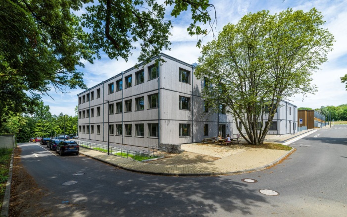 façade grise du bâtiment modulaire de l'école avec des lattes de bois verticales