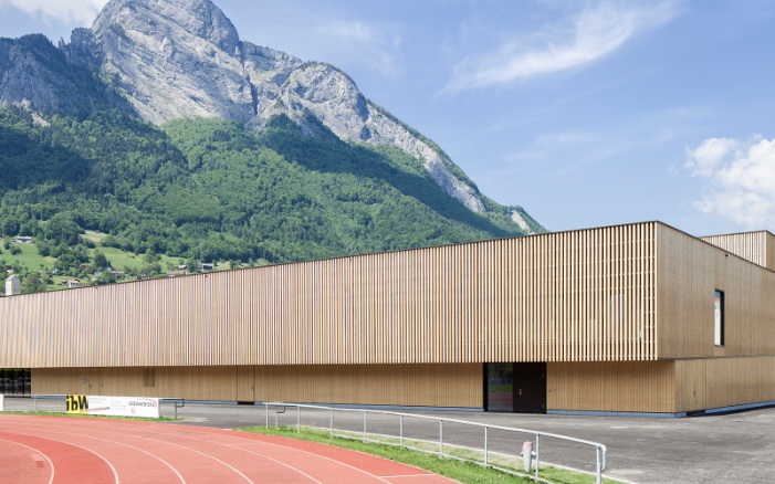 RSA Sargans sports hall with tartan track in the foreground and mountain backdrop.