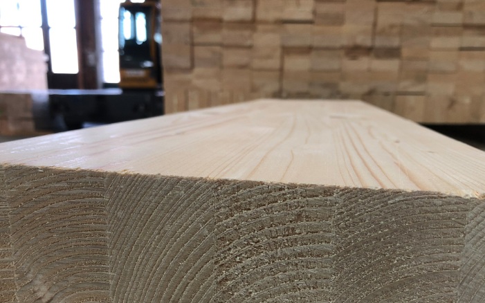 Close-up of laminated timber with stack of wood in the background