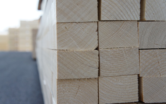 Double slats stacked in the open air, with wood in the background