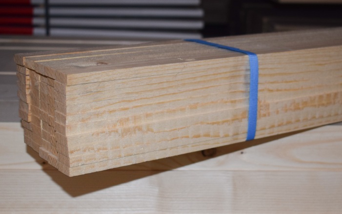 Eine Packung Gipslatten längsseitig sichtbar auf einem Holzstapel