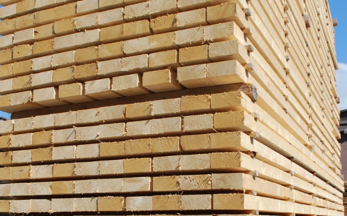 Stack of square timber in the open air, with blue sky in the background