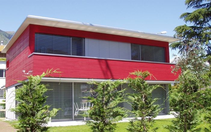 Full view of a detached house featuring red rhomboid cladding with tongue and groove.