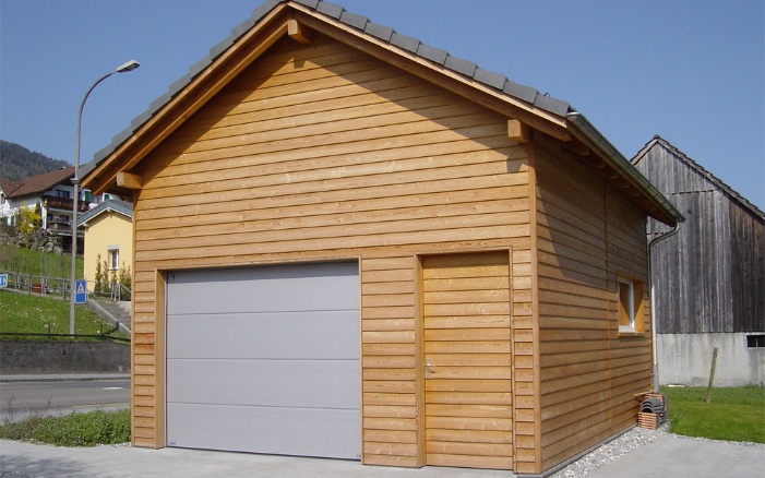 Front view of a garage with weatherboarding next to a road