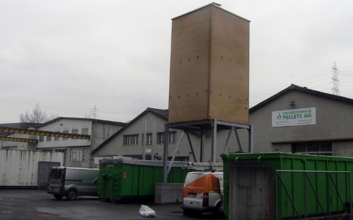 Viereckiger Silo aus Holz für die Lagerung von Pelltes neben Pellets-Produktionsfirma platziert