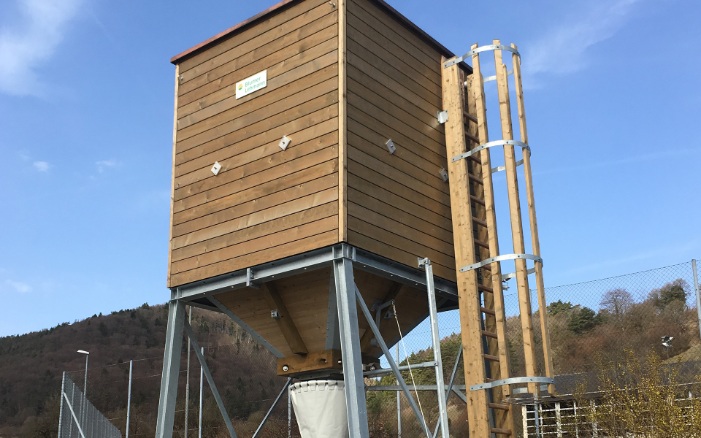 Small 20 m³ four-sided timber silo with wooden ladder on steel substructure with concrete base