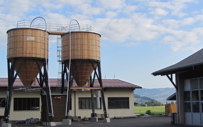 Zwei runde 100 m³ Silos aus Holz mit Stahlleiter und Dachpodium aus Stahl auf Werkhofareal platziert