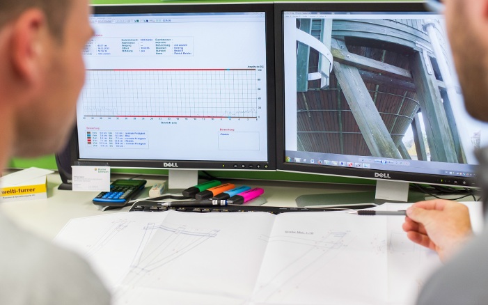 Two people in front of two screens, inspecting photos and data from a silo inspection