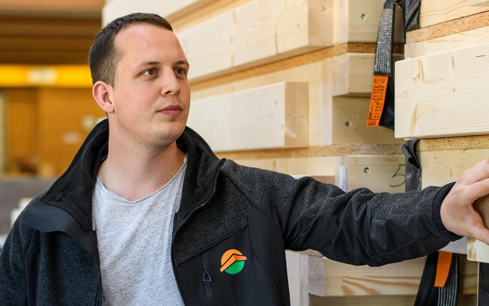 A young man standing in front of completed wall elements, checking them and concentrating on the load platform.