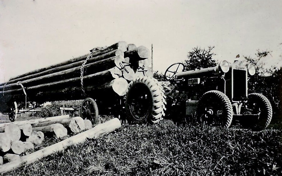 Very old photo of a tractor transporting logs