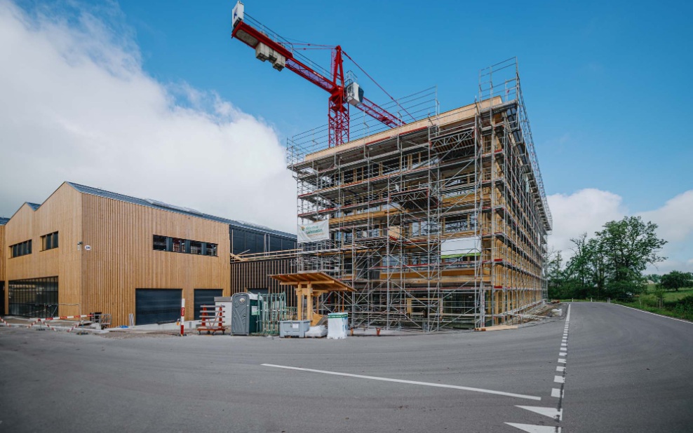 Baustelle des neuen Blumer Lehmann Stammhauses in Gossau mit Holzfassade, Gerüst und Baukran