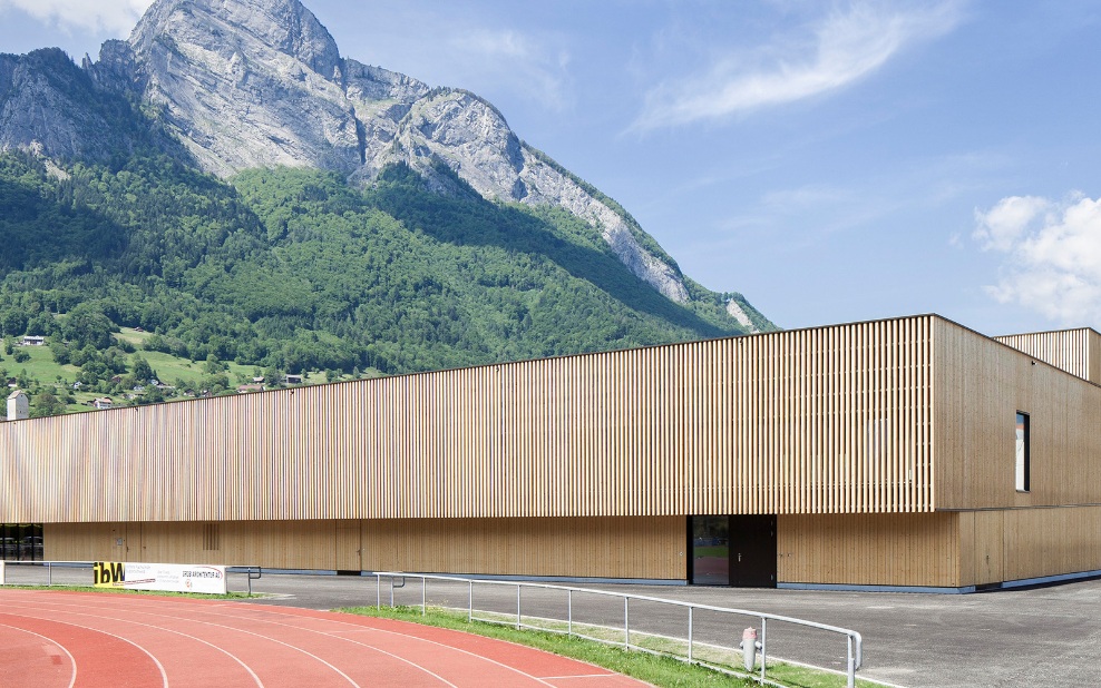 Turnhalle des RSA Sargans mit Tartanbahn im Vordergrund und Bergmassiv im Hintergrund.