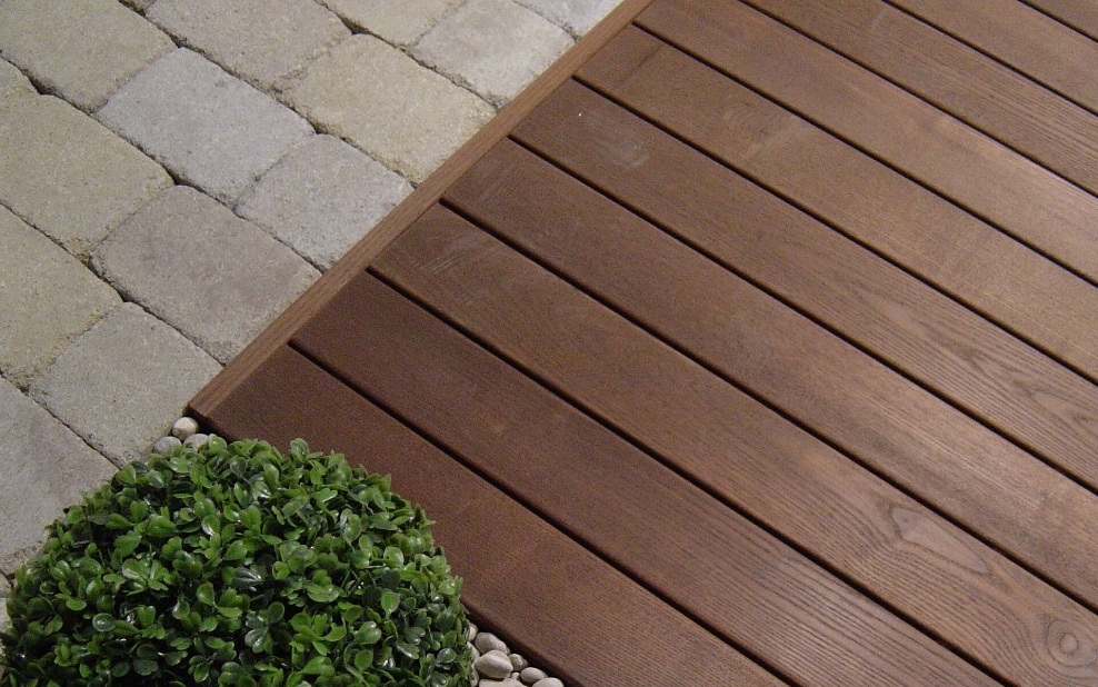 Vue détaillée d’une terrasse en bois dur à côté d’une plante verte avec jardin de rocaille